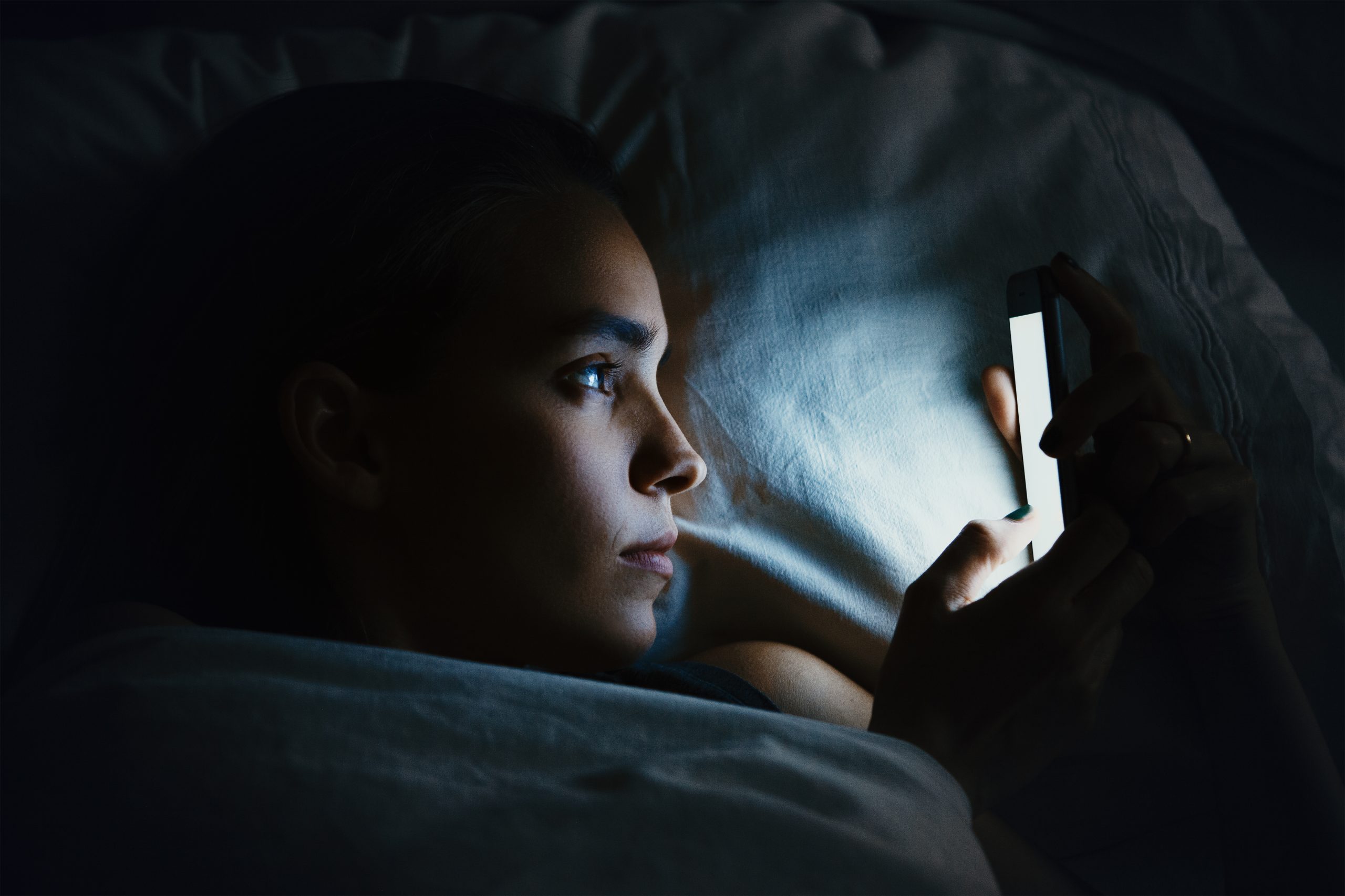 A woman in bed looking at her phone