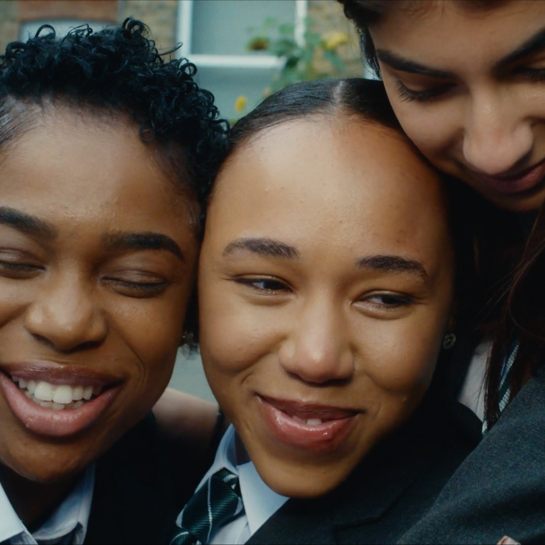 Three schoolgirls smiling and hugging