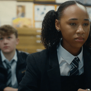 A Black schoolgirl in a classroom sat in front of a white schoolboy