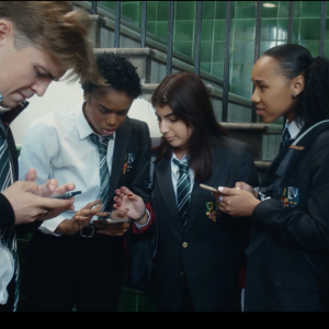 A group of young people in school looking at their mobile phones
