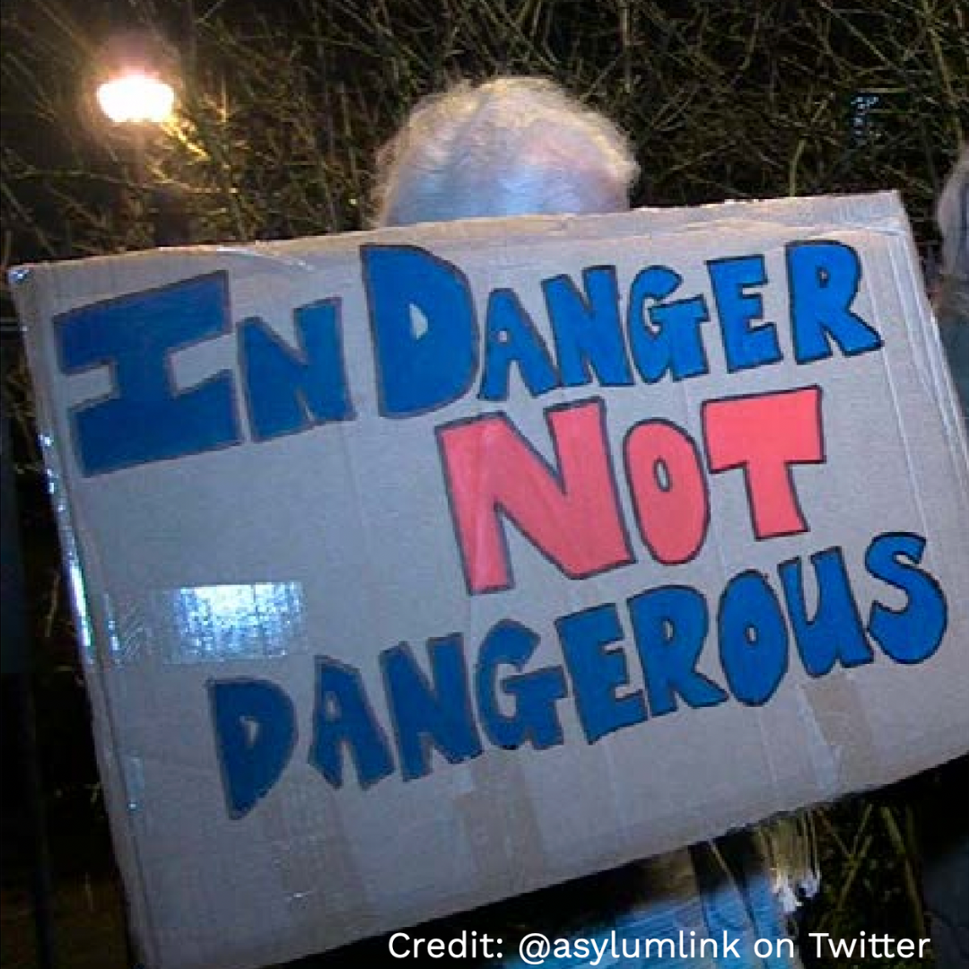 A person holding a placard that says 'in danger, not dangerous'